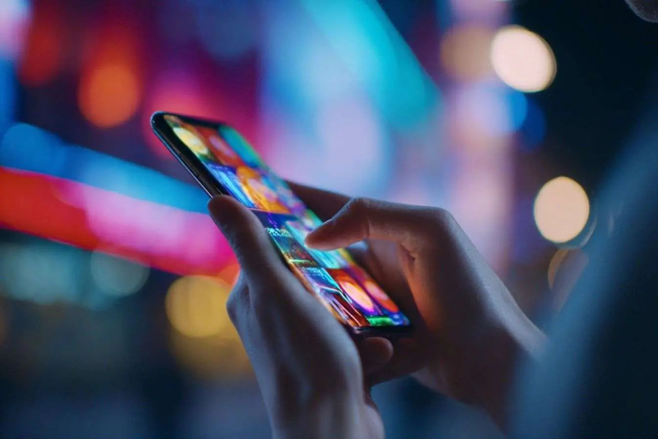 Smartphone moderne avec écran AI lumineux sous lumières néon.