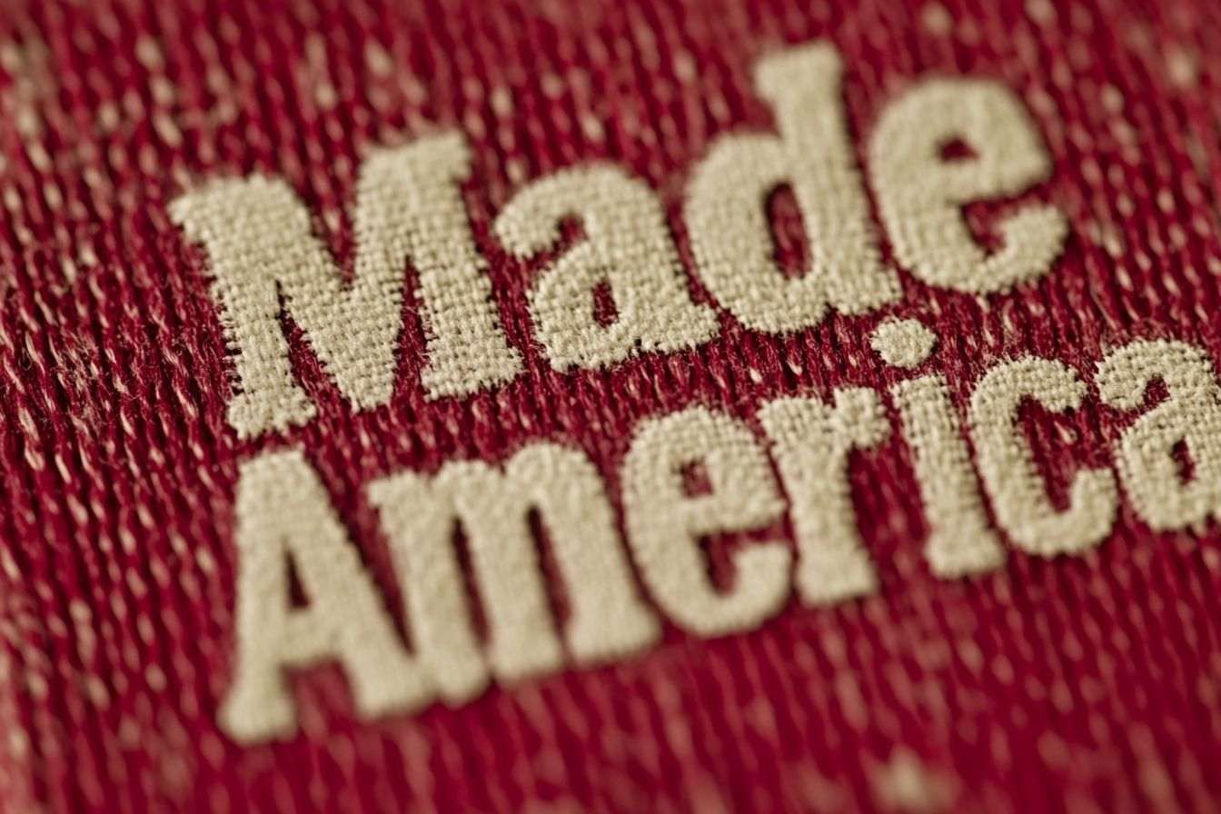 This image is an artistic portrayal featuring iconic American symbols encircling the "Made in America" phrase, all set on a vibrant red canvas.